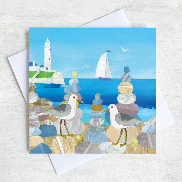 Greetings card featuring two seagulls on a beach with st mary's lighthouse in the background.