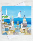 Greetings card featuring two seagulls on a beach with st mary's lighthouse in the background.