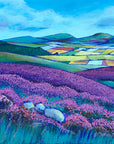 A landscape painting of the simonside hills.  Swathes of purple heather are painted in the forground with a patchwork of colourful fields in the valley below. The cheviot hills can be seen in the distance with blue skies overhead. 
