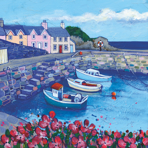 Pink flowers with green leaves capture the viewer's eye in the foreground. Three boats moored in the harbour are then visible encased by a stone brick harbour wall. With details such as steps and a metal ladder with subtle colour in the bricks. Houses in beautiful shades of orange, pink and cream can be observed beyond Dunure’s harbour wall. With a cliff face and darker ocean visible towards the back of the image.  