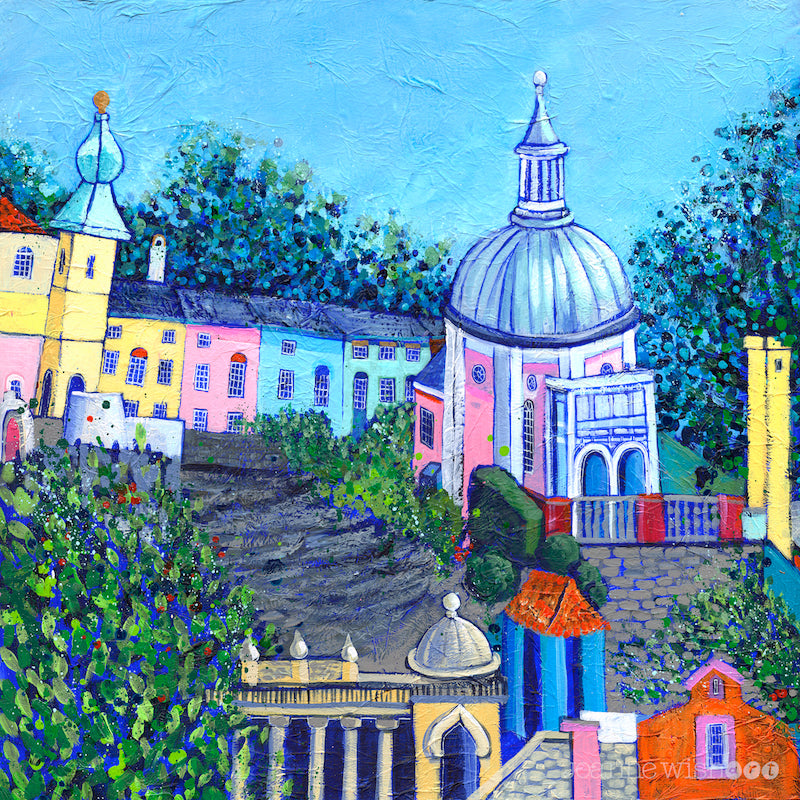 Portmeirion is an italian village on the welsh coast. In this colourful painting you can see buildings of blue green pink and yellow perched on the mountainside. The sky is blue and the buildings are interspersed with leafy green trees. 