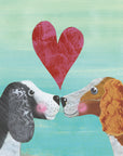 Two friendly spaniel dogs face each other blushing with a big textured red heart between them. One dog has black fur while the other has auburn. Both dogs have a white face and chest and curly haired ears. The background is textured blue and cream. 