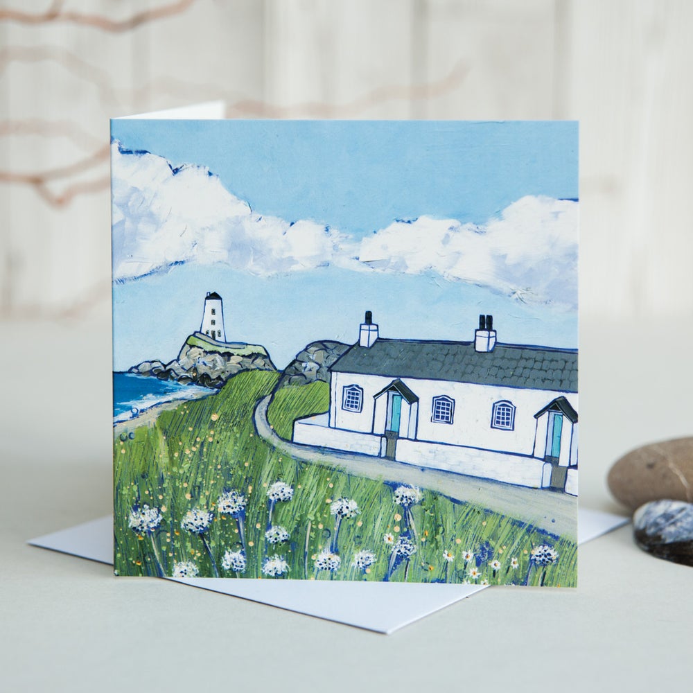 A greetings card featuring a painting of the white cottages and lighthouse on Llanddwyn Island off Anglesey.