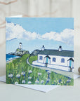 A greetings card featuring a painting of the white cottages and lighthouse on Llanddwyn Island off Anglesey.